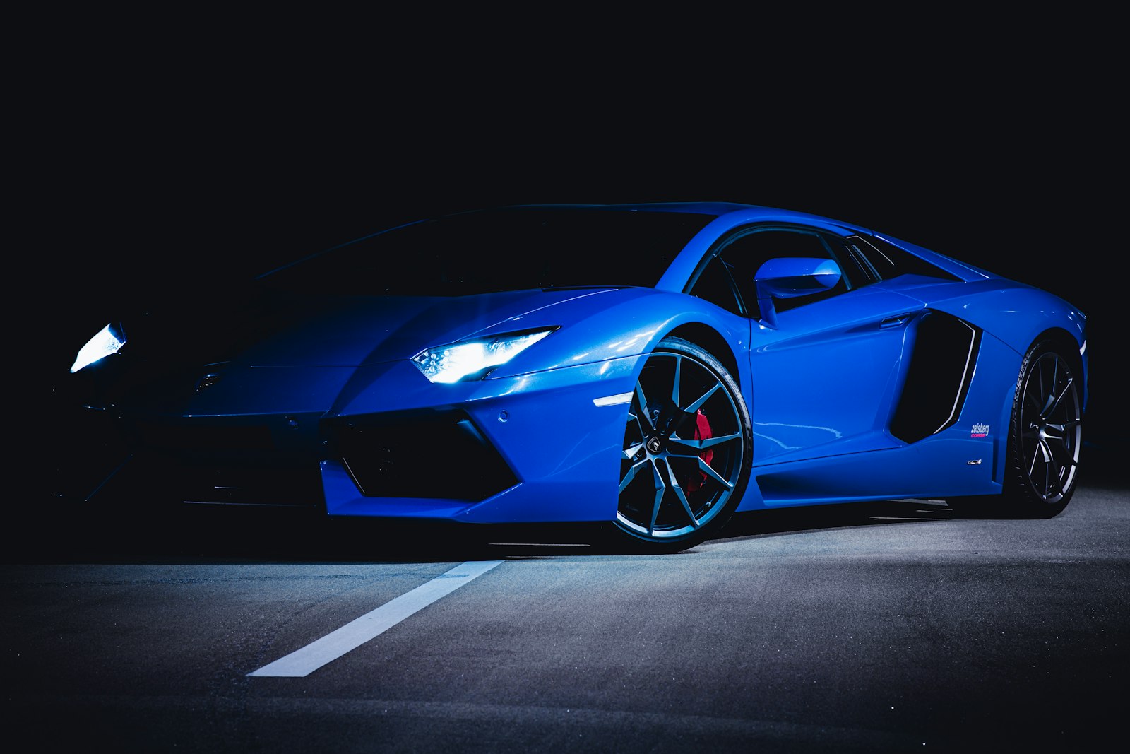 Blue Lamborghini Aventador lit against a dark background